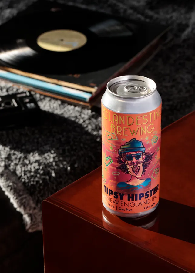 Can of Clandestine Brewing Tipsy Hipster New England IPA on a wood surface beside a record player