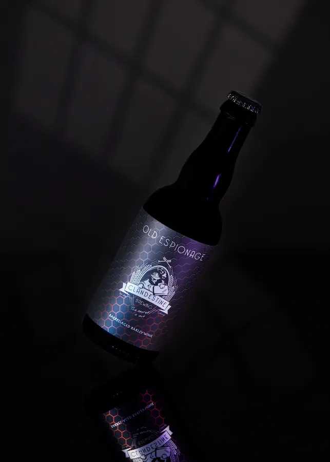 Bottle of Clandestine Brewing Old Espionage barrel-aged barley wine on a dark reflective surface
