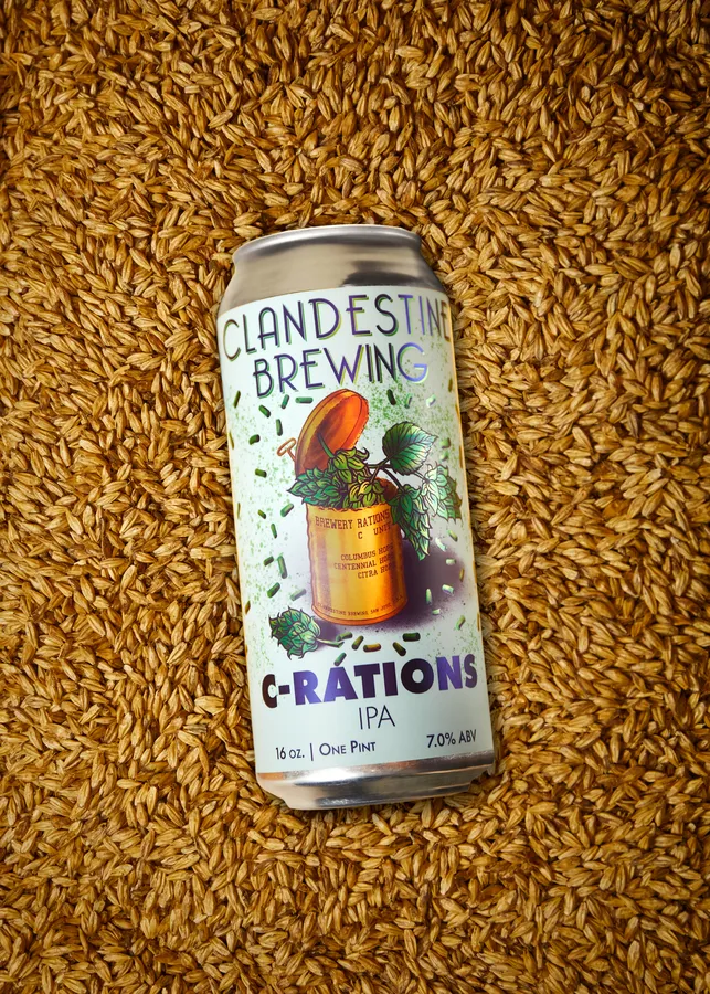 Can of Clandestine Brewing C-Rations IPA resting on a bed of malted barley grains